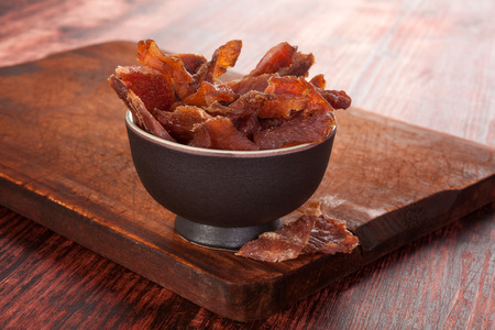 Beef jerky. Dried meat beef jerky on wooden chopping board on wooden background. Dry meat, rustic country style. Delicious meat eating. Stockfoto