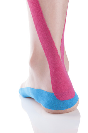 Kinesio tape on female heel isolated on white background.