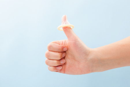 condom on thumb up gesture female hand with thums up and condom