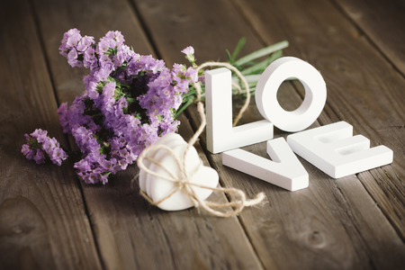 Cute love words and beautiful delicate flowers on rustic wooden table