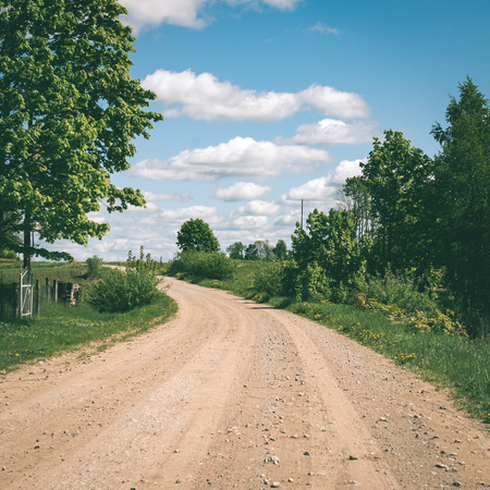 砂利の道フットパス牧草地、木と美しい空と田舎へ右折の写真素材