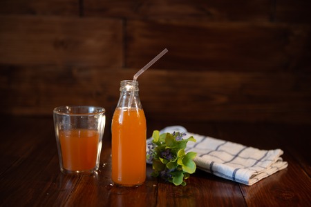 vintage bottle with juice, straw, flowers and towel on wooden table Stock Photo