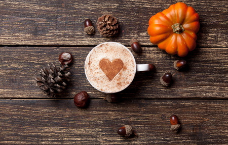 Cup of coffee with heart shape and pine cone with acorn and pumpkin on wooden background - 43008602