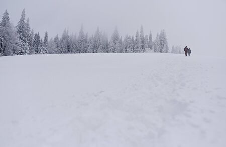 Couple hiking through a snow covered field in the wintertime