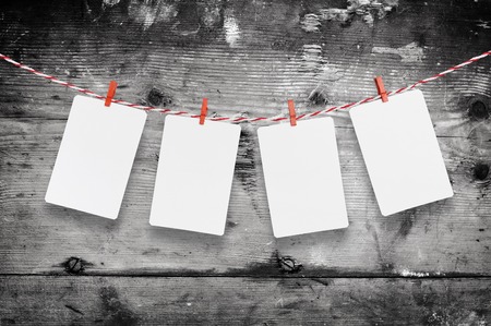 Blank paper or photo frames hanging on the red striped clothesline on wooden background template for your text