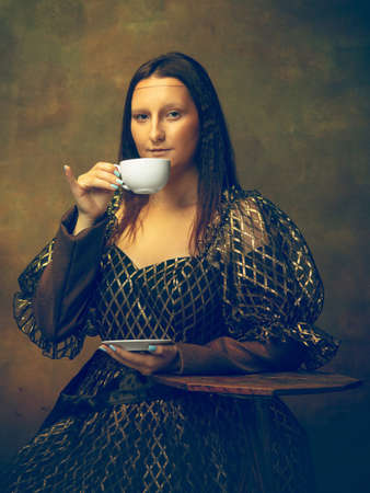 Czas na kawę. młoda kobieta jako mona lisa, la gioconda na ciemnozielonym tle. styl retro, porównanie koncepcji epok. piękna modelka o klasycznym historycznym charakterze, staromodna. Zdjęcie Seryjne