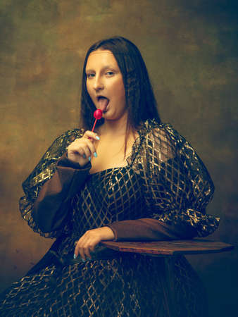 Cukierek. młoda kobieta jako mona lisa, la gioconda na ciemnozielonym tle. styl retro, porównanie koncepcji epok. piękna modelka o klasycznym historycznym charakterze, staromodna.