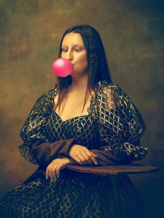Guma balonowa. młoda kobieta jako mona lisa, la gioconda odizolowana na ciemnozielonym tle. styl retro, porównanie koncepcji epok. piękna modelka jak klasyczna postać historyczna, staromodna.