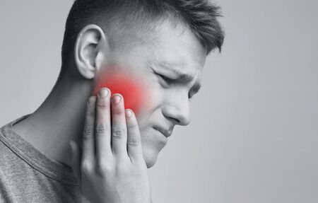 Problem stomatologiczny. młody mężczyzna cierpiący na silny ból zęba, monochromatyczne zdjęcie z czerwoną strefą zapalną, wolna przestrzeń
