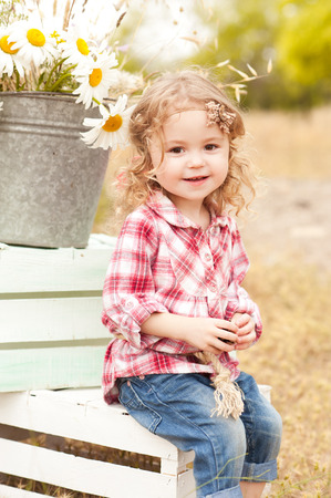 cute baby girl sitting on crates with decorations outdoors stock
