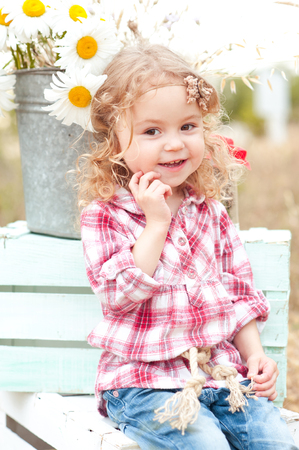 cute baby girl sitting on crates with flowers outdoors stock photo