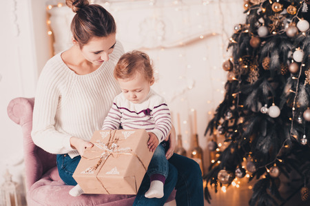 smiling young mother open christmas presents with baby girl 1 year old under christmas tree - Christmas Presents For 1 Year Old smiling young mother open christmas presents with baby girl 1 year old under christmas tree - Christmas Presents For 1 Year Old