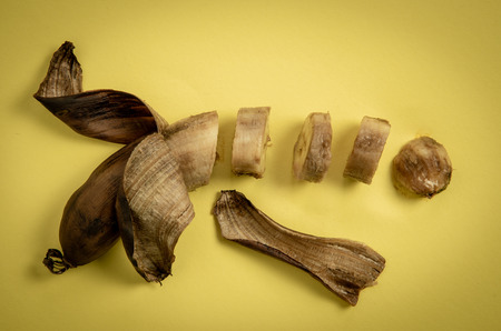 Slices of rotten unhealthy banana on a yellow background Stock Photo