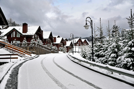 Wooden cottages holiday house in mountain holiday resort covered with fresh snow in winter beautiful winter street after snowfall