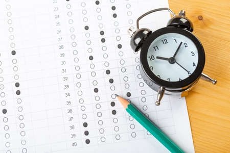 Answer sheet, test in exercise and passing examination paper computer sheet with pencil alarm clock and pencil for education concept