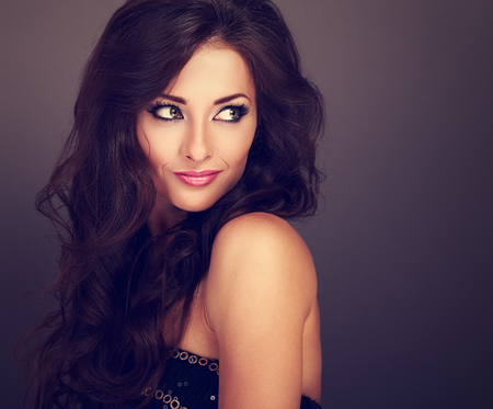 Beautiful bright makeup woman with curly long hair style looking on empty copy space. Toned closeup portrait Фото со стока