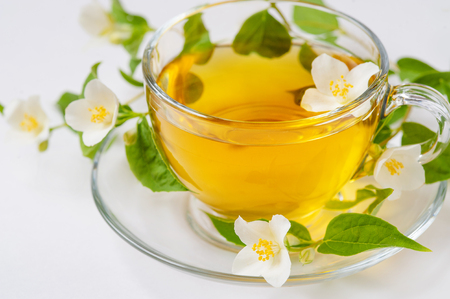 A cup of jasmine tea with jasmine flowers on a wooden background