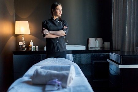 Massage: Массажист стоит у bassage tavle с скрестив руки и глядя за окном