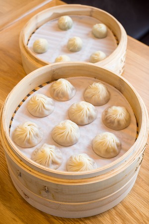 chinese steamed bun in bamboo steamer on wooden table stock photo
