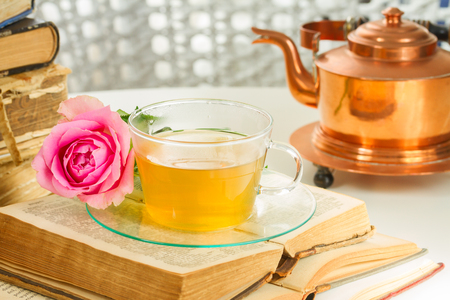 ガラスのティーポットとカップでお茶を開く古い本とバラの花 の写真素材 画像素材 Image