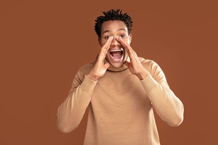 Happy African Man Shouting To The Camera Posing On Brown Studio