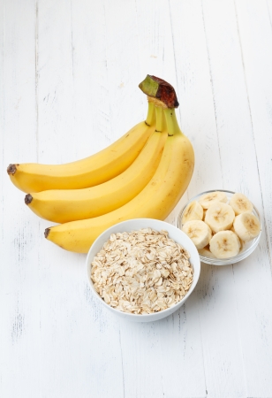 banana: Bowl mảnh yến mạch với chuối thái lát trên bàn gỗ