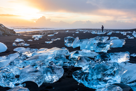 Diamond beach en islande avec des icebergs bleus fondant sur le sable noir et la glace scintillant avec la lumière du soleil du lever du soleil, touriste regardant de beaux paysages naturels arctiques, côte sud de l'islande, jokulsarlon Banque d'images