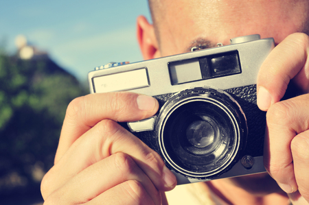 Primo piano di un giovane uomo di scattare una foto con una vecchia macchina fotografica all'aperto Archivio Fotografico - 34294670