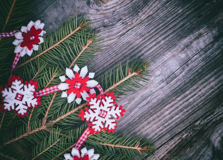 Christmas garland of spruce branches and the felt snowflakes on a red ribbon vintage toning