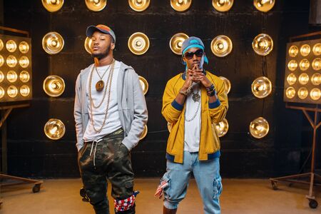 Two black rappers in caps, perfomance on stage