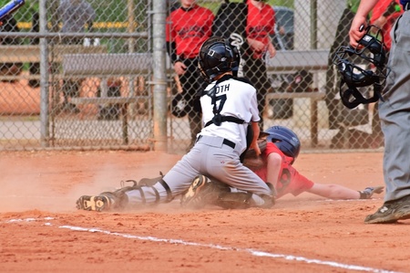 Cumming, GA, USA - April 19, 2010 - A little league baseball catcher tagging the runner out on homeplate at a game in Forsyth County, Cumming GA, 4-10-2010.  A regular season game between the Bulldogs and the Raiders. - 8780178