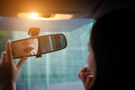 背面ミラーを見て 車でメイクアップを置く若い女性 現代の忙しい生活 メイクをしている車の運転席に座っている美しい少女は 口紅を適用します の写真素材 画像素材 Image 4037