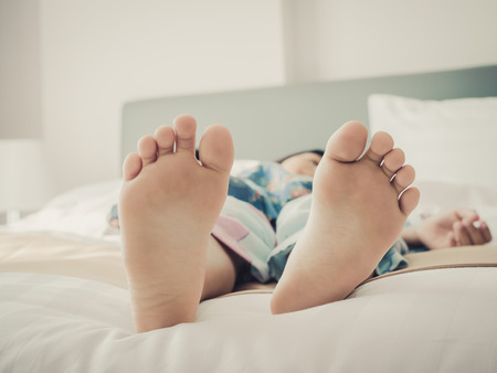 Young kid bare feet in bed with vintage tone, dept of field.