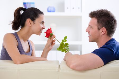 Romantic man giving red rose to woman - Valentines Day. Фото со стока