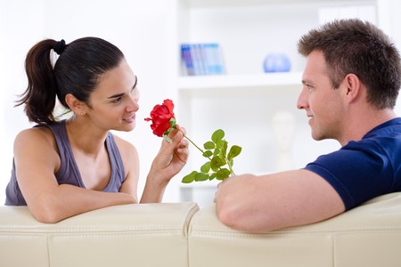 Romantic man giving red rose to woman - Valentines Day. Фото со стока