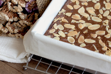 homemade dark chocolate brownies topping almond slices in square baking sheet cover