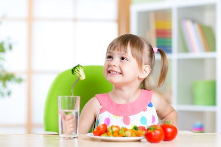 Kind isst gesunde Gemüsemahlzeit im Haus oder in der Baumschule Stockfoto