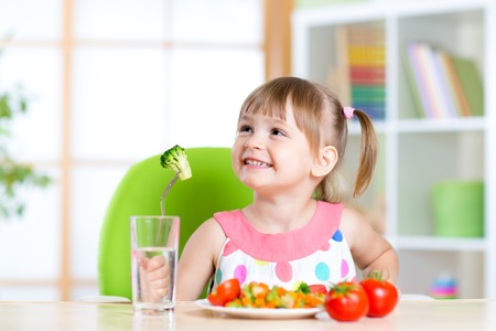 Kid eats healthy vegetables meal in home or nursery - 44977171