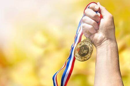 Gold medal with ribbon in hand on background