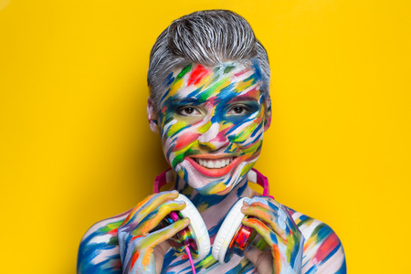 人の歌を聞くヘッドフォン 塗装面の明るいアート ボディアート Faceart 女性の美しい少女を占めています カラフルな音楽イコライザーの写真の明るい背景 リズム メロディーのパーティー タイムの世界 の写真素材 画像素材 Image