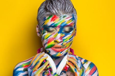 人の歌を聞くヘッドフォン 塗装面の明るいアート ボディアート Faceart 女性の美しい少女を占めています カラフルな音楽イコライザーの写真の明るい背景 リズム メロディーのパーティー タイムの世界 の写真素材 画像素材 Image