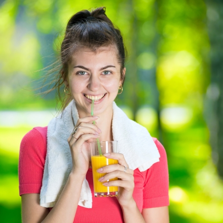 緑の夏の公園でスポーツ フィットネス運動後若い女性飲酒の新鮮なオレンジ ジュース の写真素材 画像素材 Image