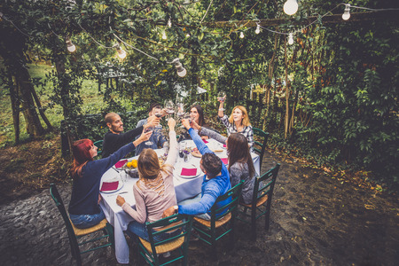 Gruppe Freunde am Restaurant draußen - Leute, die in einem Hausgarten zu Abend essen