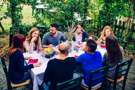 Gruppe Freunde am Restaurant draußen - Leute, die in einem Hausgarten zu Abend essen