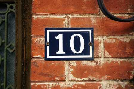 Enameled house number ten on a red brick wall Enameled house number ten on a red brick wall