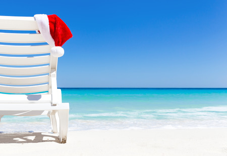 santa claus hat on sunbed near tropical calm beach with turquoise caribbean sea water and white - Summer Christmas santa claus hat on sunbed near tropical calm beach with turquoise caribbean sea water and white - Summer Christmas