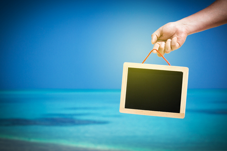 empty board with copy space hanging in hand on beach tropical