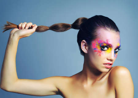 Warrior queens wear makeup like war paint. studio shot of an attractive young woman with brightly colored makeup against a blue background.