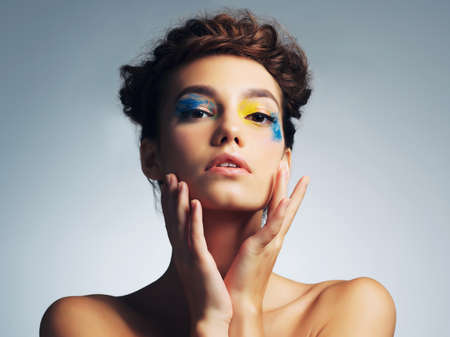 Eye makeup that makes an impact. studio shot of an attractive young woman with brightly colored makeup against a gray background.