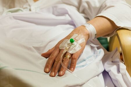 Pacjentka w szpitalu leczona przez obwodowy cewnik do transfuzji dożylnej. zbliżenie dłoni i ramienia prawdziwych ludzi. Zdjęcie Seryjne